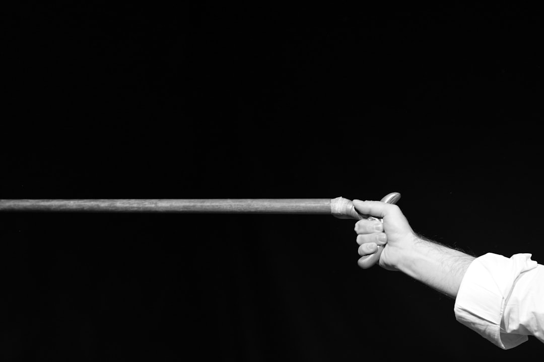 Photo by luca romano Hand holding a long wooden stick against black background